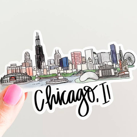 Sticker of Chicago skyline with 'Chicago, IL' text held by a hand on a light gray background