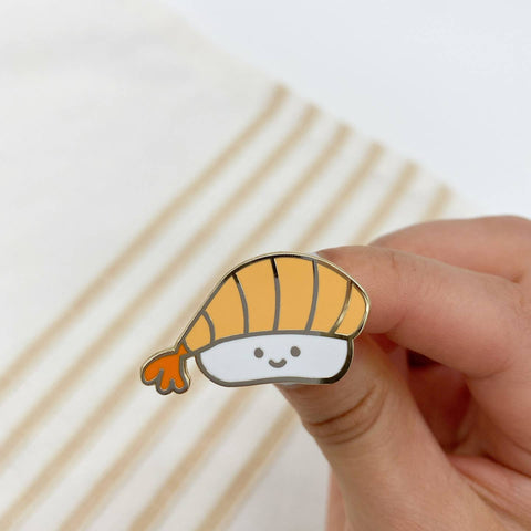 Hand holding a cartoon-style mushroom pin with a white background