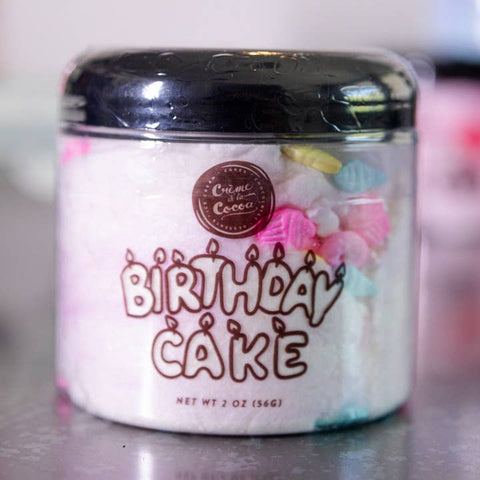 Jar of 'Birthday Cake' flavored candy with colorful sprinkles on a reflective surface.