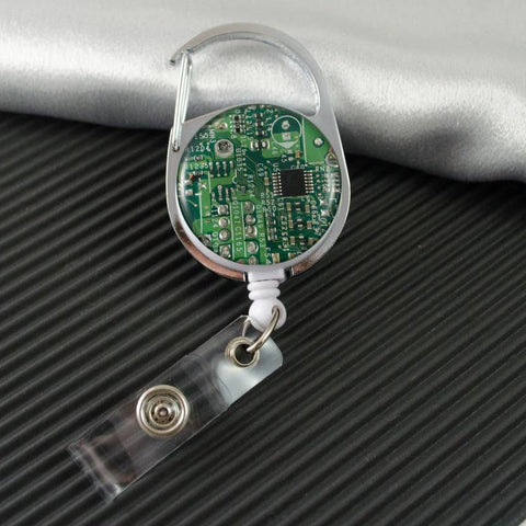 Retractable badge holder with green circuit board design on a textured surface
