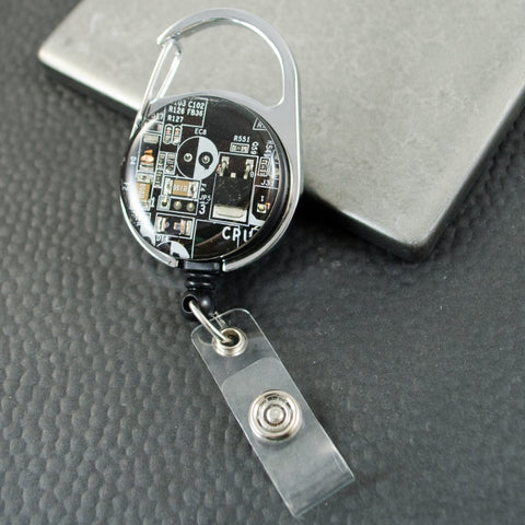 Retractable badge holder with electronic component design on a gray surface