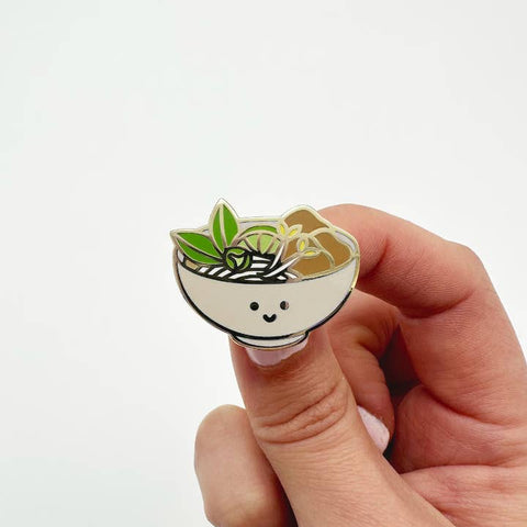 Hand holding a small round badge with a cartoon-style plant design on a white background