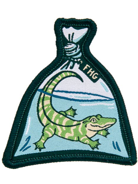 Embroidered patch with a green alligator in a glass jar labeled 'FHG' on a white background.