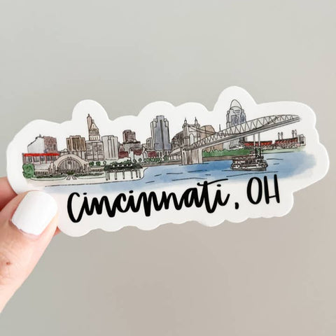 Sticker of Cincinnati, OH skyline held by a hand on a gray background