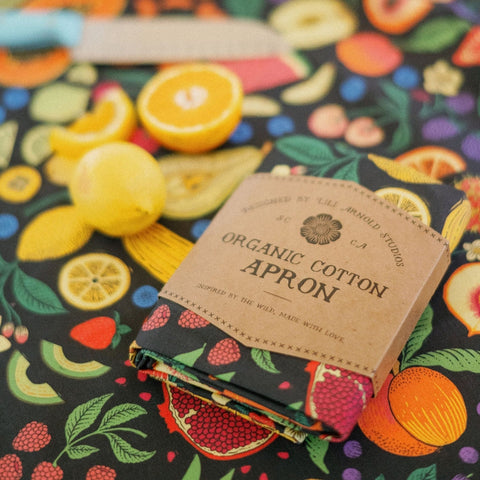 Organic cotton apron on a colorful fruit-patterned tablecloth