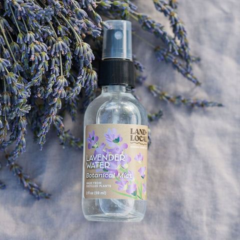 Bottle of Lavender Water Botanical Mist with lavender flowers on a textured surface