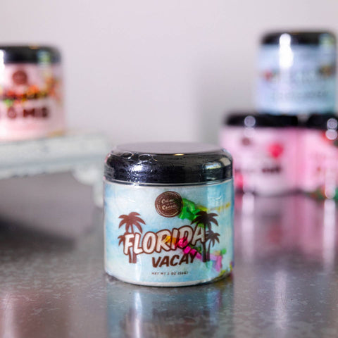 Jar labeled 'Florida Vacay' on a reflective surface with blurred background