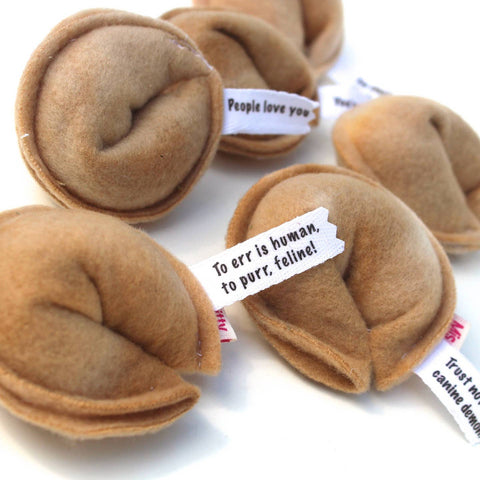 Brown plush fortune cookies with humorous text tags on a white background