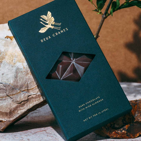 Green chocolate packaging with a geometric chocolate piece on a natural background