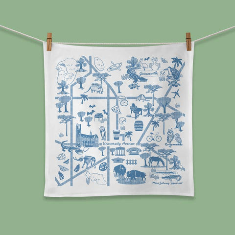 White towel with blue graphics of Jacksonville, FL, hanging on a line against a green background