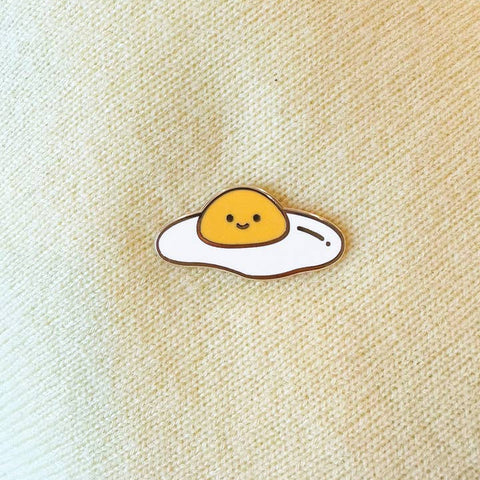 Cartoon-style fried egg with a smiling face on a beige fabric background