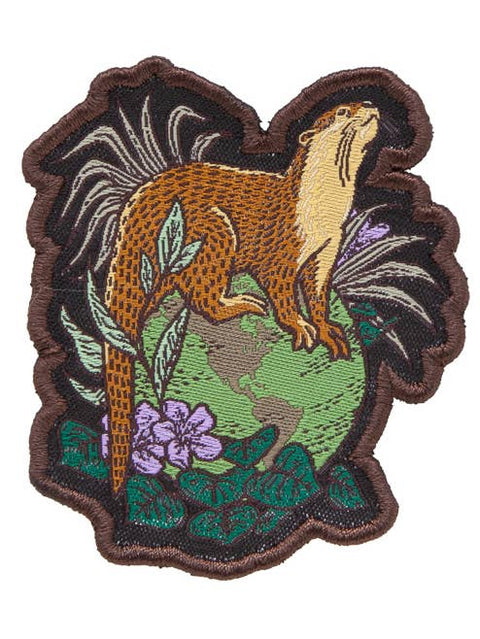 Embroidered patch of a beaver in a natural setting with leaves and flowers.