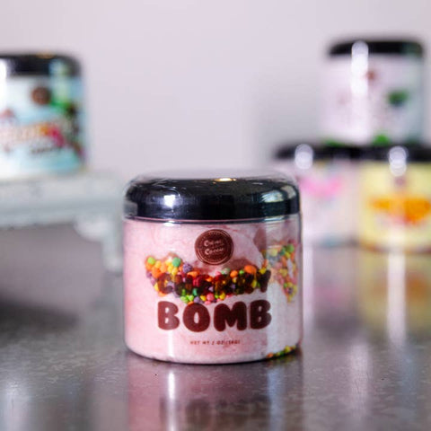 Jar labeled 'BOMB' with colorful sprinkles on a reflective surface