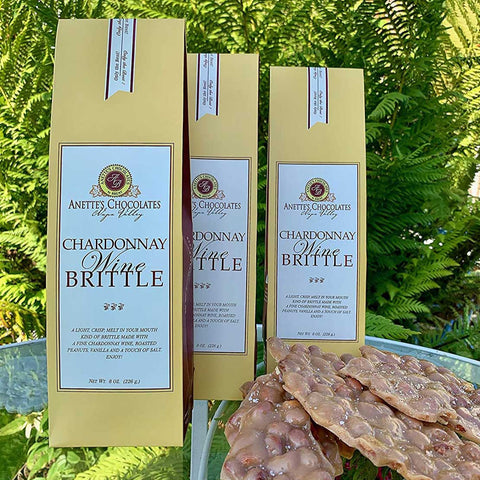 Three boxes of Chardonnay Wine Brittle with a label on a green leafy background