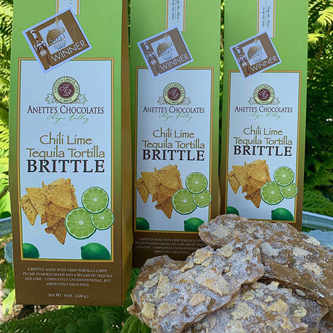 Three boxes of Anette's Chocolates Chili Lime Tequila Tortilla Brittle with brittle in front.