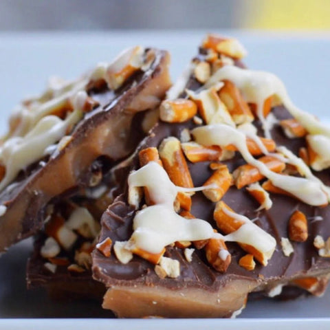 Chocolate bark with pretzels and white drizzle on a white plate
