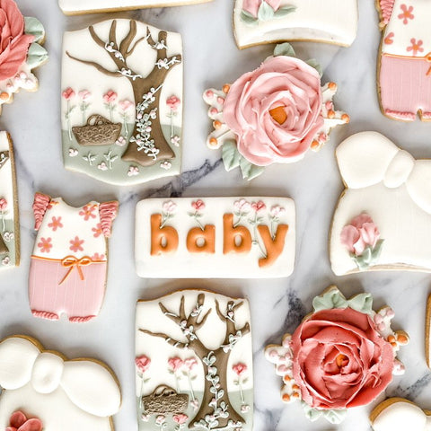 Decorative cookies with floral designs, gift boxes, and 'baby' text on a white surface.