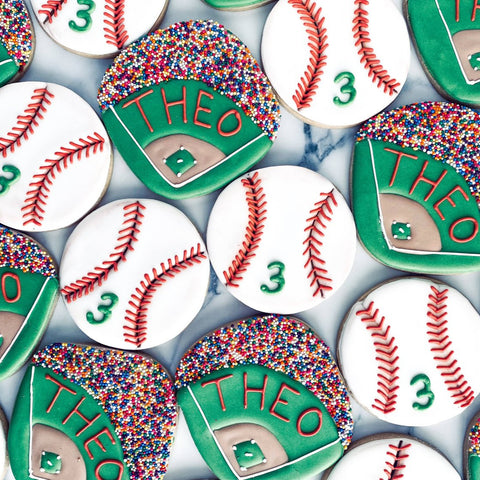 Cookies shaped like baseballs and bases with 'THEO' and number '3' on a white background