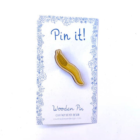 Wooden spoon-shaped pin on a 'Pin it!' card with decorative border