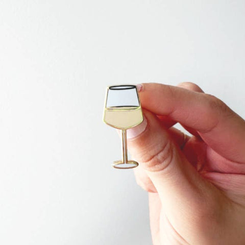 Hand holding a small wine glass-shaped object against a white background