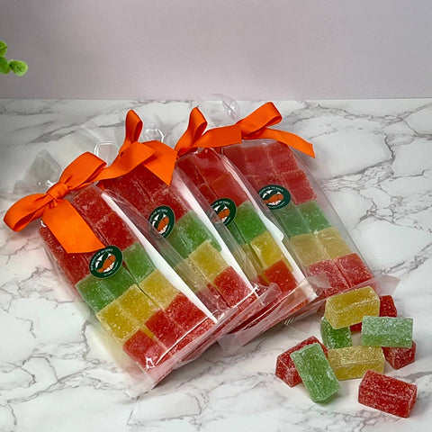 Packaged gummy candies with orange ribbons on a marble surface