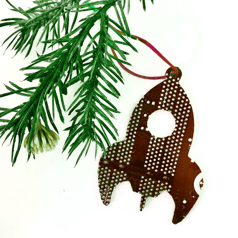 Decorative reindeer ornament with polka dot pattern hanging on a green branch.