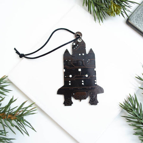 Black decorative ornament shaped like a castle on a white background with greenery