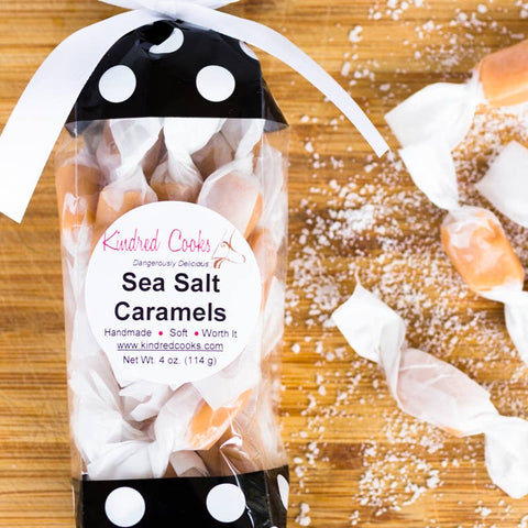 Packaged sea salt caramels with a 'Kindred Cooks' label on a wooden surface.