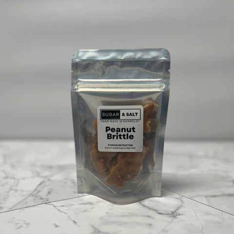 Packaged peanut brittle with 'Sugar & Salt' label on a marble surface