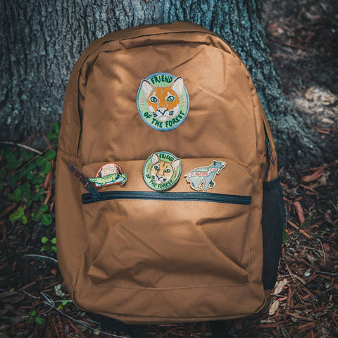 Brown backpack with animal-themed patches on a natural background