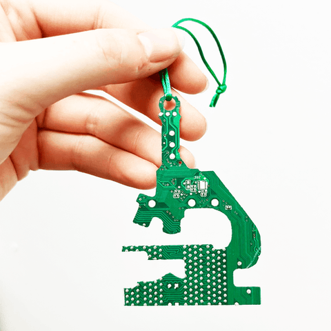 Hand holding a green circuit board shaped like a number '4' against a white background