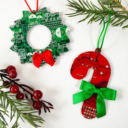 Christmas ornaments made from recycled circuit boards with greenery and berries on a white background