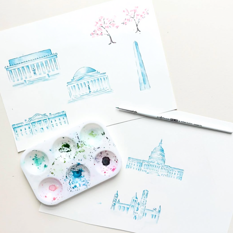 Artistic illustrations of buildings on paper with a watercolor palette and brush.