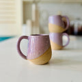 Two ceramic mugs with a gradient design on a light surface.