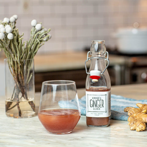 Bottle of ginger ale with a glass of ginger ale on a kitchen counter.