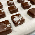 Chocolate candies with sea salt on a white surface