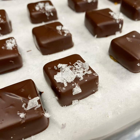 Chocolate candies with sea salt on a white surface