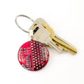 Keychain with a red circuit board design and a key on a white background