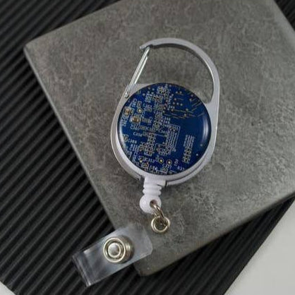 Retractable badge holder with blue circuit board design on a textured surface
