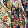 Colorful fabric with fruit pattern held by a hand on a white background