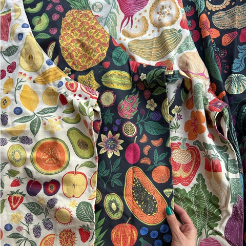Colorful fabric with fruit pattern held by a hand on a white background