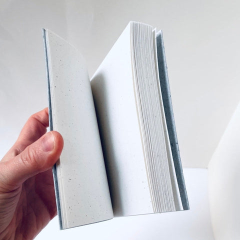 Hand holding a stack of white paper against a white background