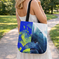 Woman carrying a tote bag with a blue and green abstract design outdoors.