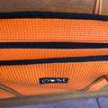 Orange suitcase with a visible brand logo on a wooden surface