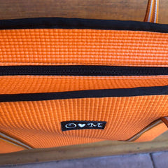 Orange suitcase with a visible brand logo on a wooden surface