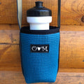 Blue textured bottle holder with a black lid on a wooden surface