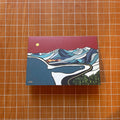 Card with a mountain and road design on a wooden surface