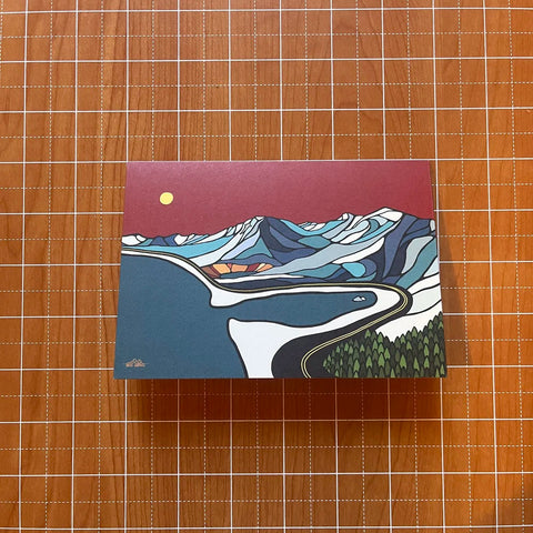 Card with a mountain and road design on a wooden surface