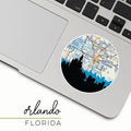 Laptop with a round sticker featuring a map of Orlando, Florida, on a white background.