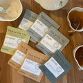 Tea set with teapot, cups, and tea bags on a wooden surface